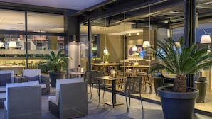 An outdoor seating area with modern furniture, potted plants, and a view of the interior space.