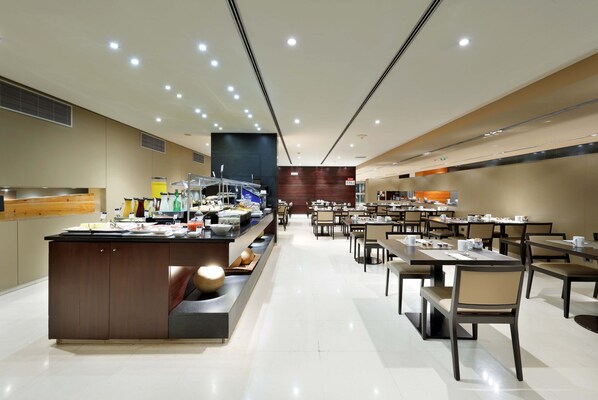 Un restaurant moderne doté d’un bar central, de nombreuses tables et d’un intérieur propre et bien éclairé.