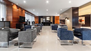 Un moderno vestíbulo de hotel con zonas de estar, una recepción y una televisión.