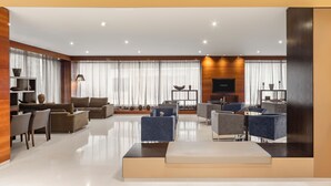Un salón amplio con diseño moderno, que cuenta con un televisor de pantalla plana grande, zonas de estar cómodas y un suelo limpio y pulido.