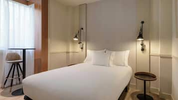 A neatly made bed with white linens in a modern hotel room.