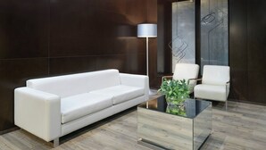 A modern living room with a white sofa, two white armchairs, a glass coffee table, and a floor lamp. - AC Hotel Zamora by Marriott (Zamora)