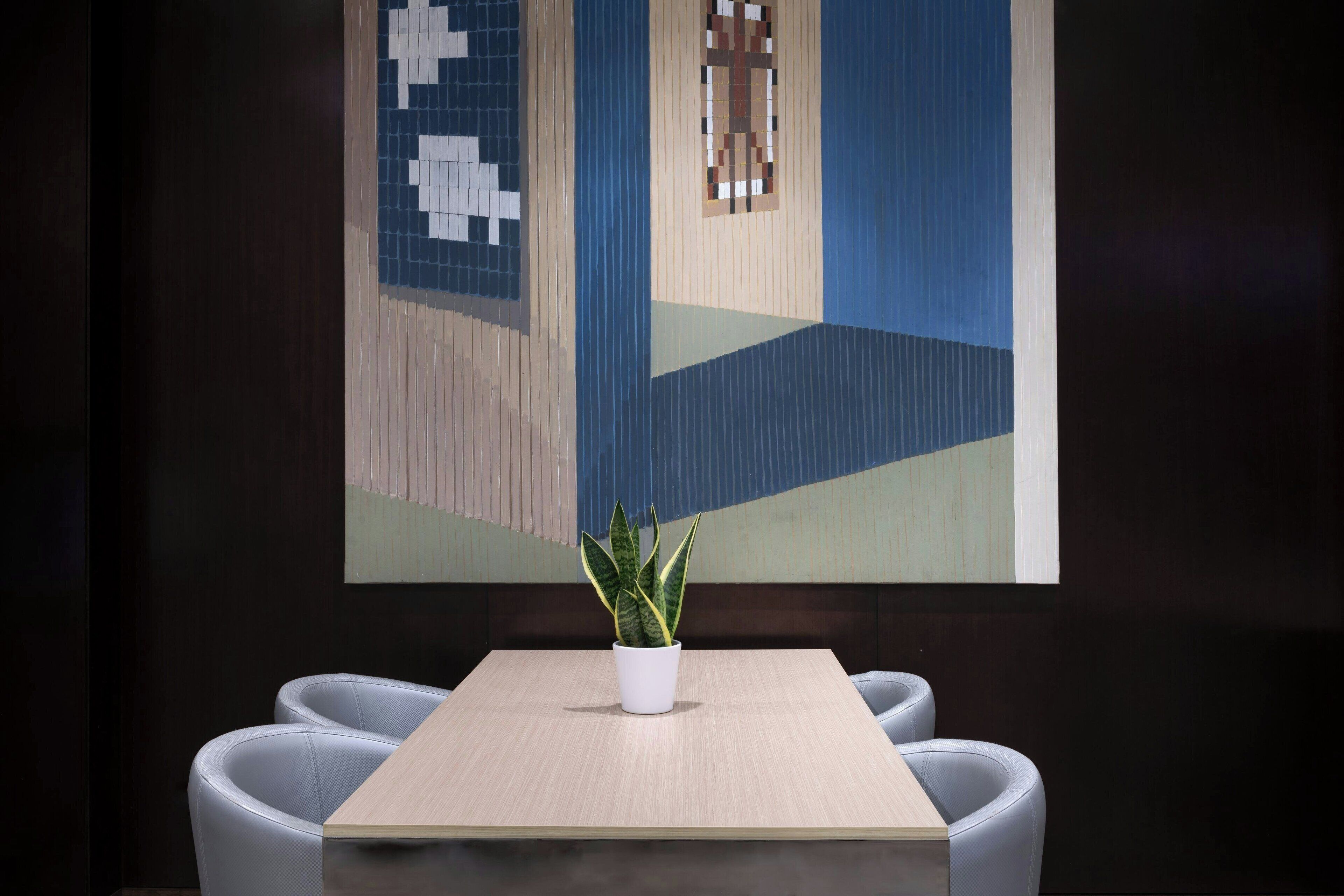 A modern room with a wooden table, two grey chairs, and a potted plant.