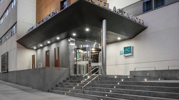 A hotel entrance with a modern design, featuring a covered entrance, a staircase, and a sign indicating it is part of the AC Hotels chain. - AC Hotel Zamora by Marriott (Zamora)