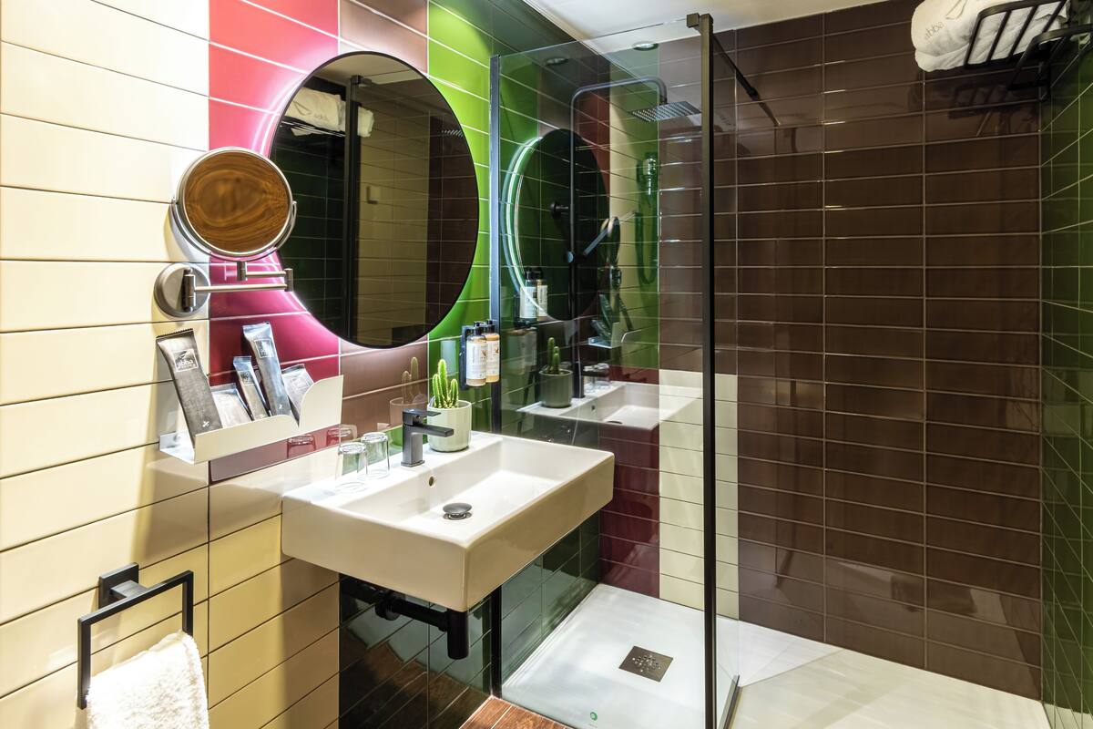 A modern bathroom with two sinks, a large mirror, and a glass shower enclosure.
