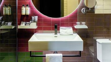 Un baño moderno con un espejo redondo, un lavabo y un inodoro.