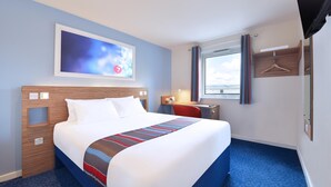 A hotel room with a large bed, a desk, a chair, a TV, and a window with curtains. - Travelodge Derby Cricket Ground (Derby)