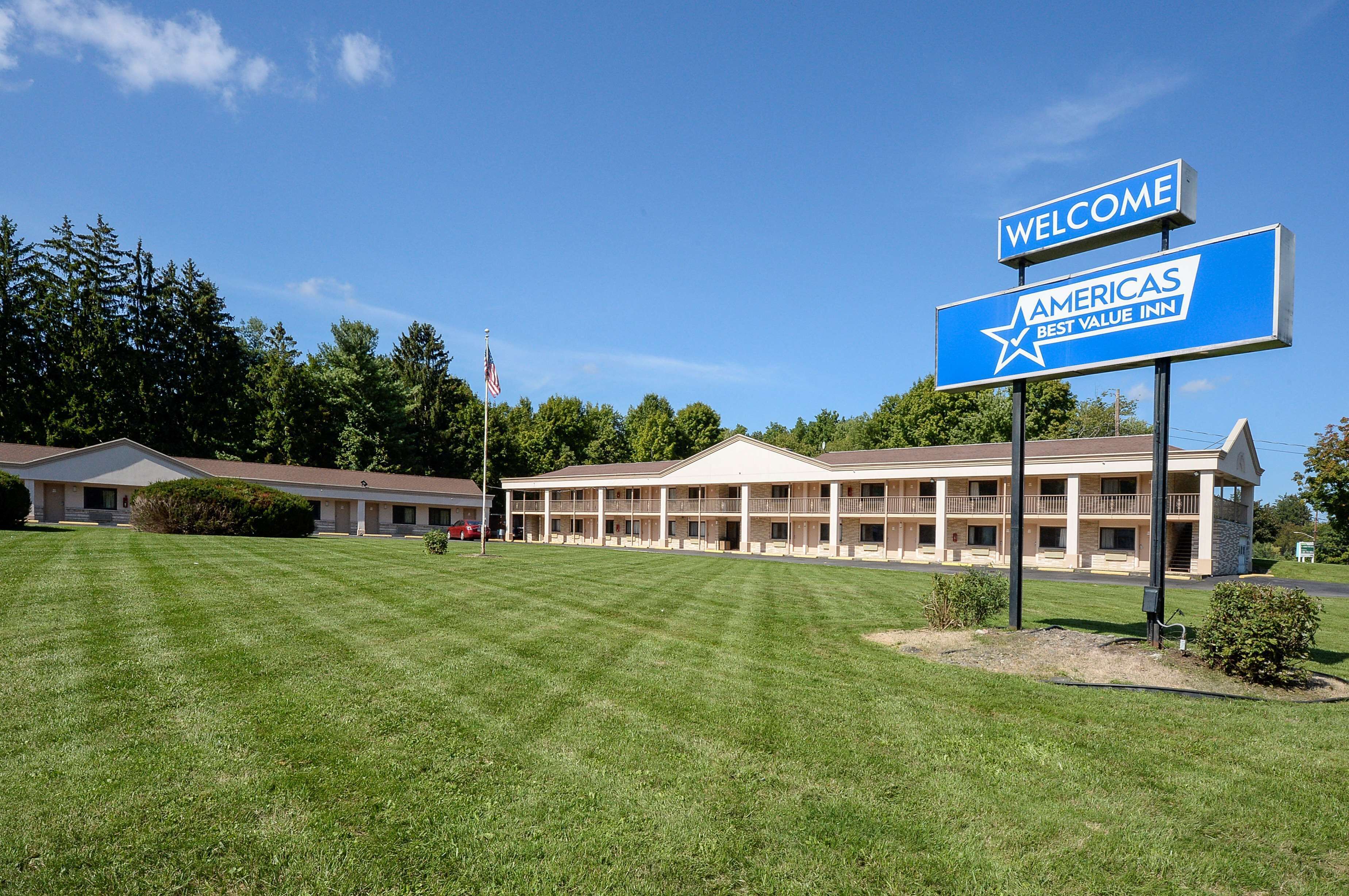 Un motel con un cartel grande que dice "Welcome to Americas Best Value Inn" y un césped bien cuidado al frente.