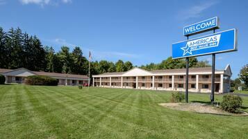 Un motel con un cartel grande que dice "Welcome to Americas Best Value Inn" y un césped bien cuidado al frente.