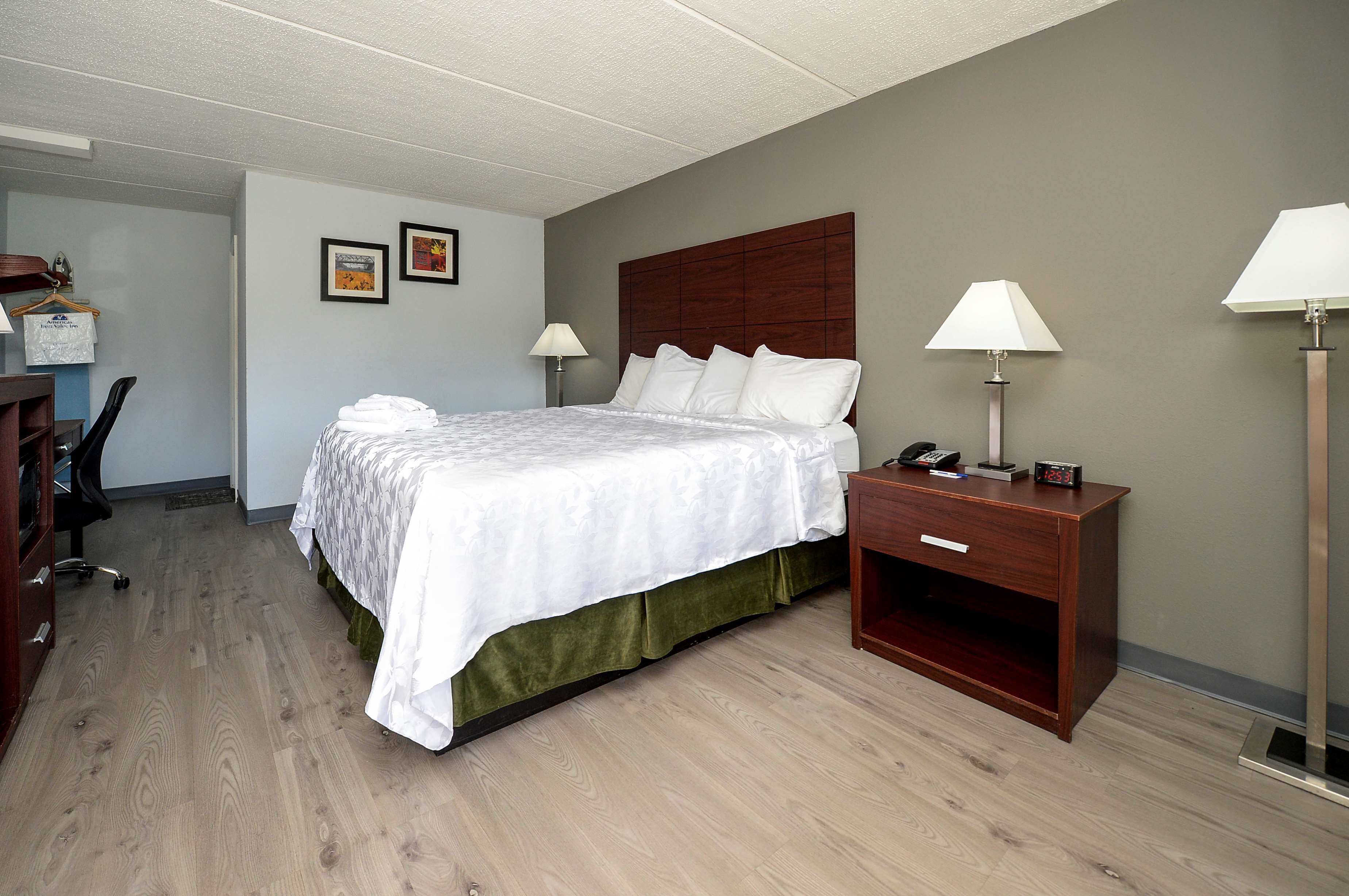 Een hotelkamer met een bed, bedlampen, een bureau met stoel en een kledingkast.