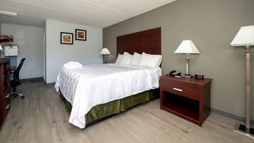 Een hotelkamer met een bed, bedlampen, een bureau met stoel en een kledingkast.
