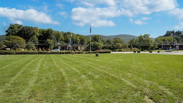 Un terrain herbeux bien entretenu, avec un mât de drapeau, un bâtiment et une montagne en arrière-plan.