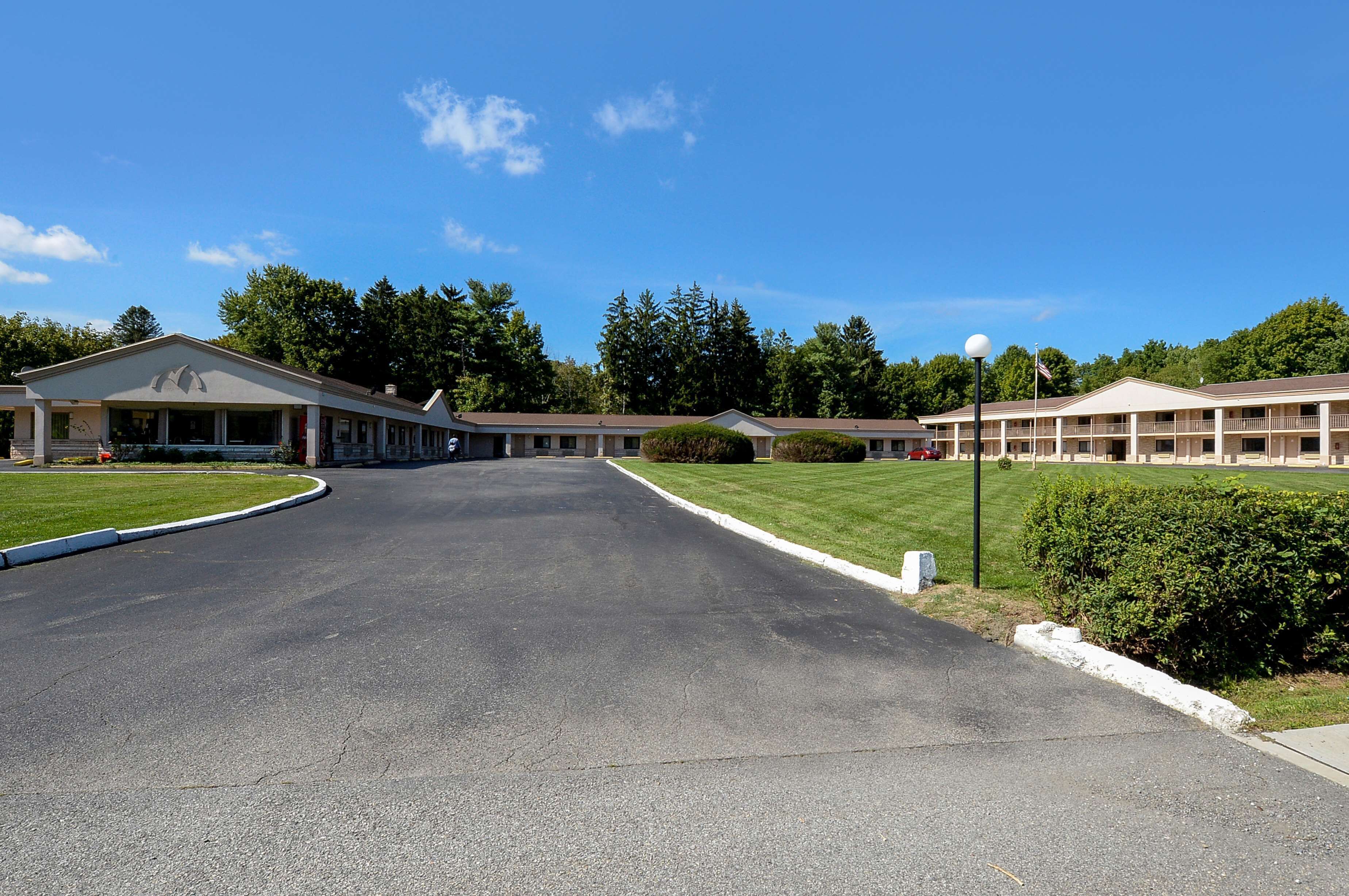 A motel with a central driveway leading to a building with a covered entrance.