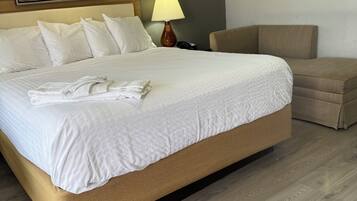 A neatly made bed with white linens, a bedside lamp, and a wooden headboard.
