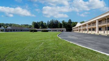 A motel with a large parking lot, a grassy area, and a building with multiple balconies.