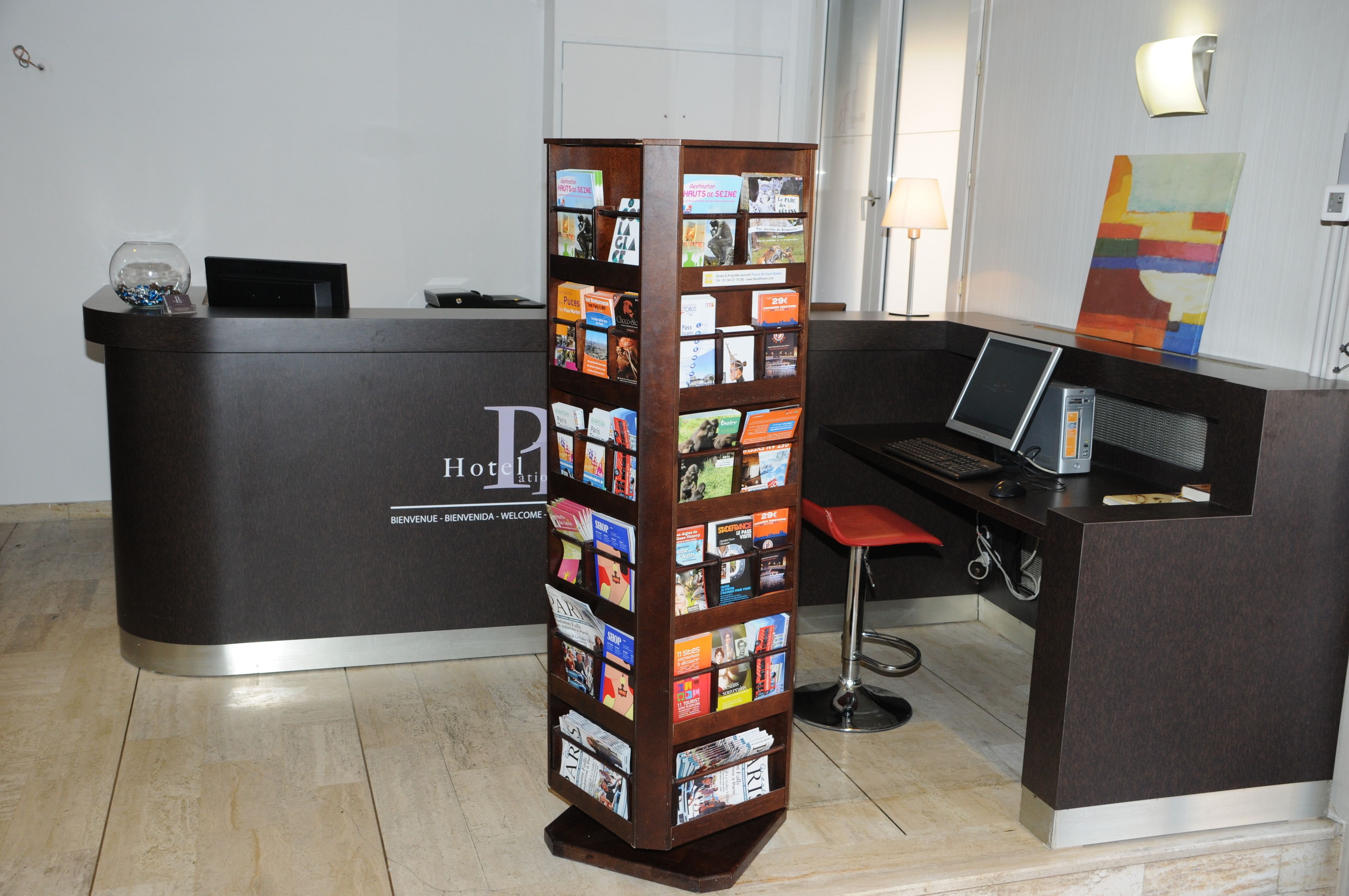 A reception desk with a dark wood finish, a glass display case, and a red bar stool.