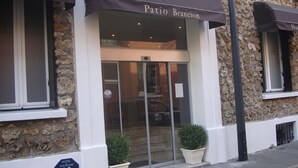 Exterior de un hotel con fachada de piedra, entrada de vidrio y un cartel que indica que es un hotel.