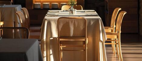 A restaurant with a large TV screen, wooden furniture, and hanging pendant lights.