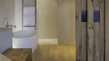 A modern bathroom with a freestanding bathtub, a wooden wardrobe, and a minimalist design.