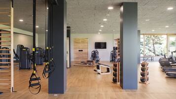 A gym with exercise equipment, wooden floors, and large windows.