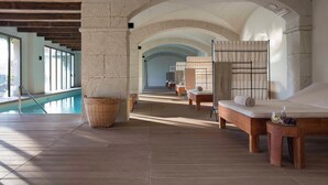 A spa area with a pool, wooden benches, and a massage table.