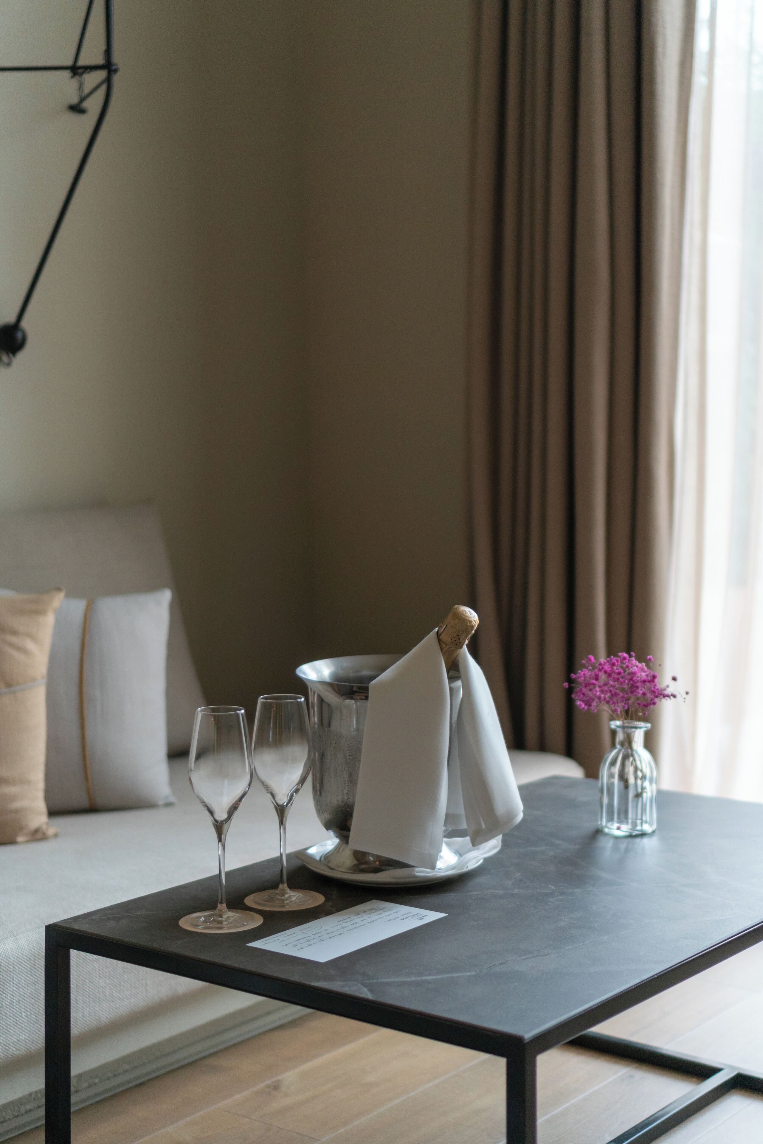 Una habitación moderna con una mesa de madera oscura, un sofá y un jarrón con flores moradas.