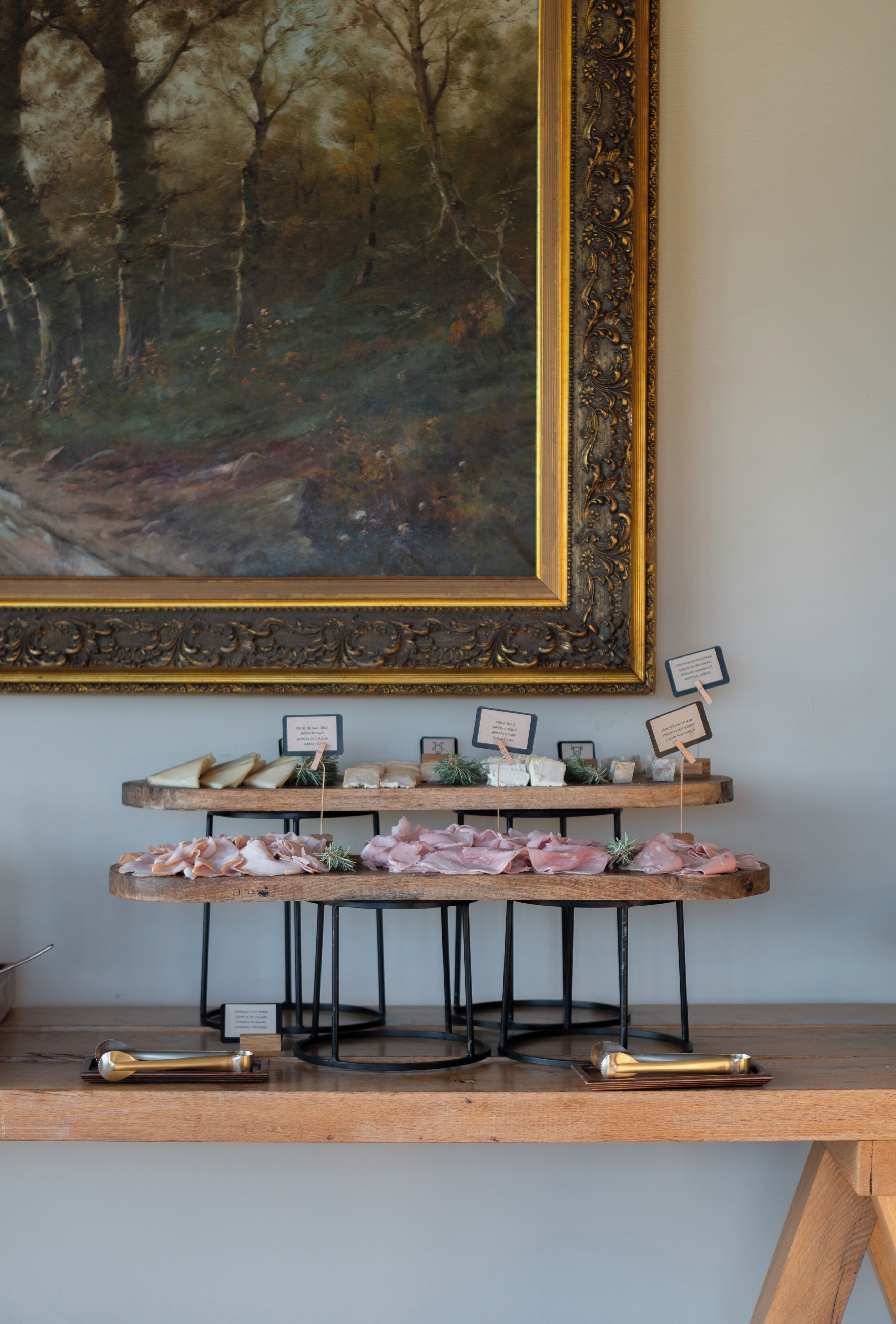 A wooden serving board with various food items and a framed painting above it.