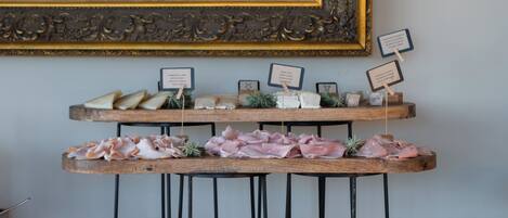 A wooden serving board with various food items and a framed painting above it.