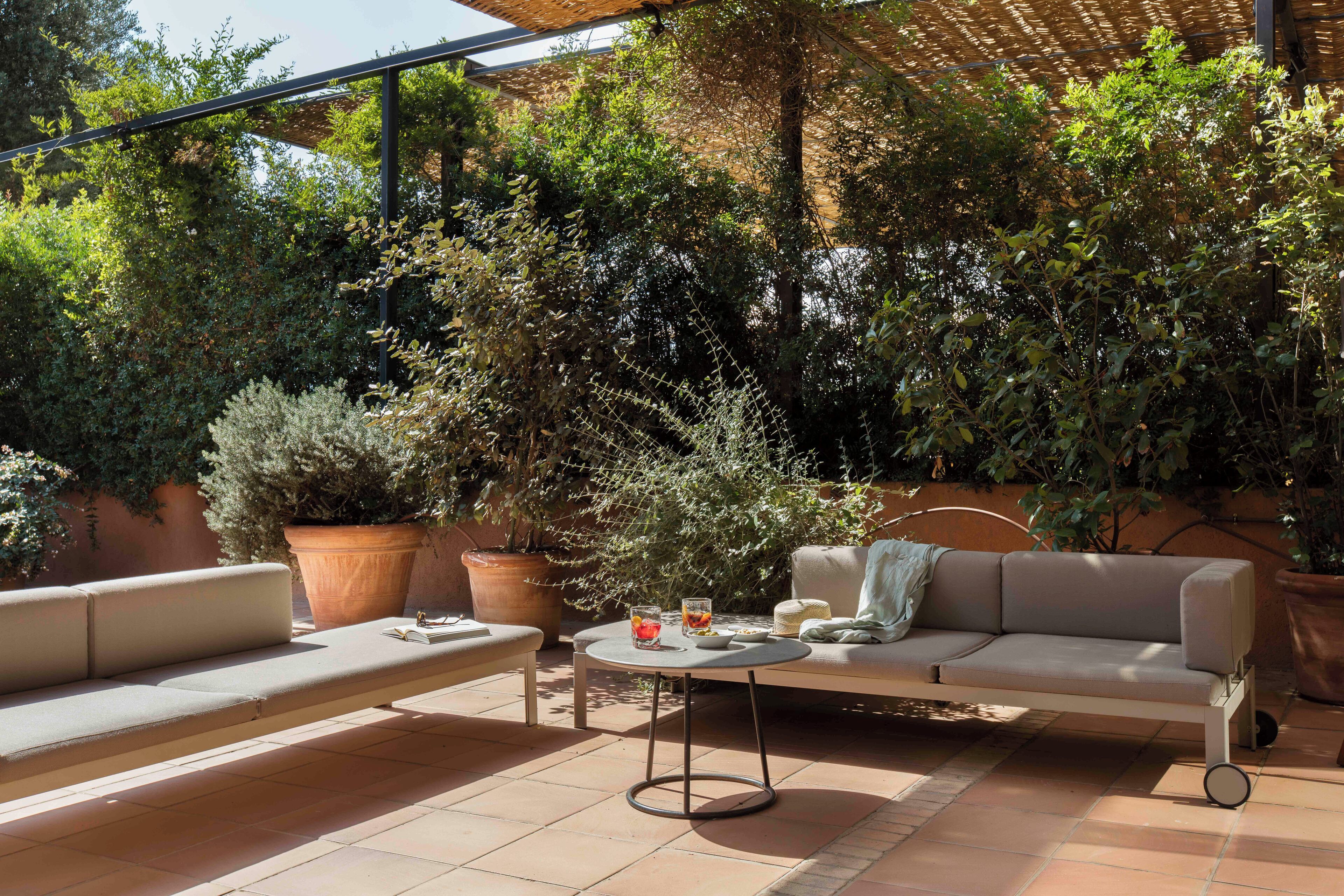 An outdoor patio with a sofa, a round table, and potted plants.