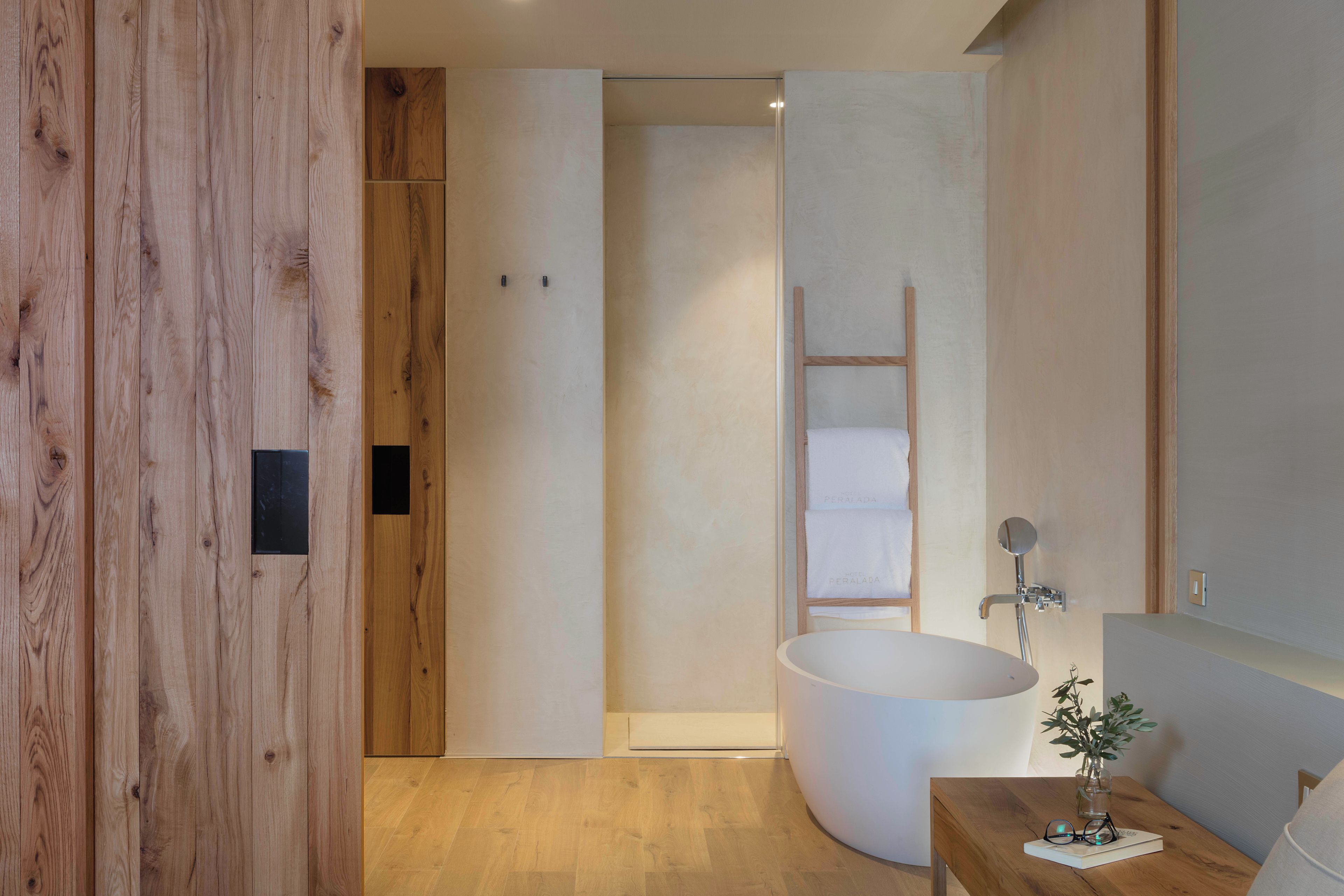 Un baño moderno con una bañera independiente, suelo de madera y un diseño minimalista.