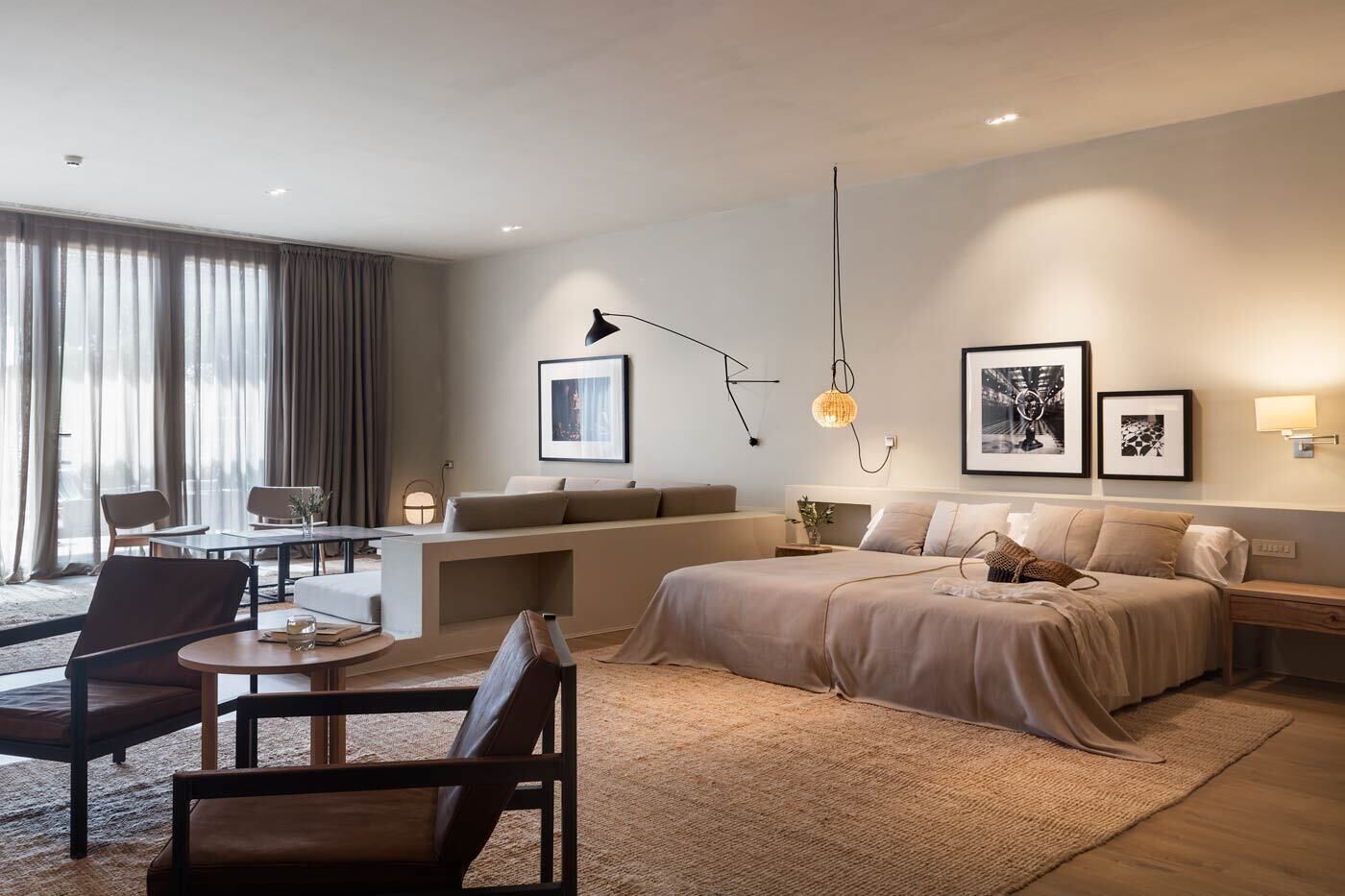 A modern hotel room with a large bed, a desk, and a seating area.