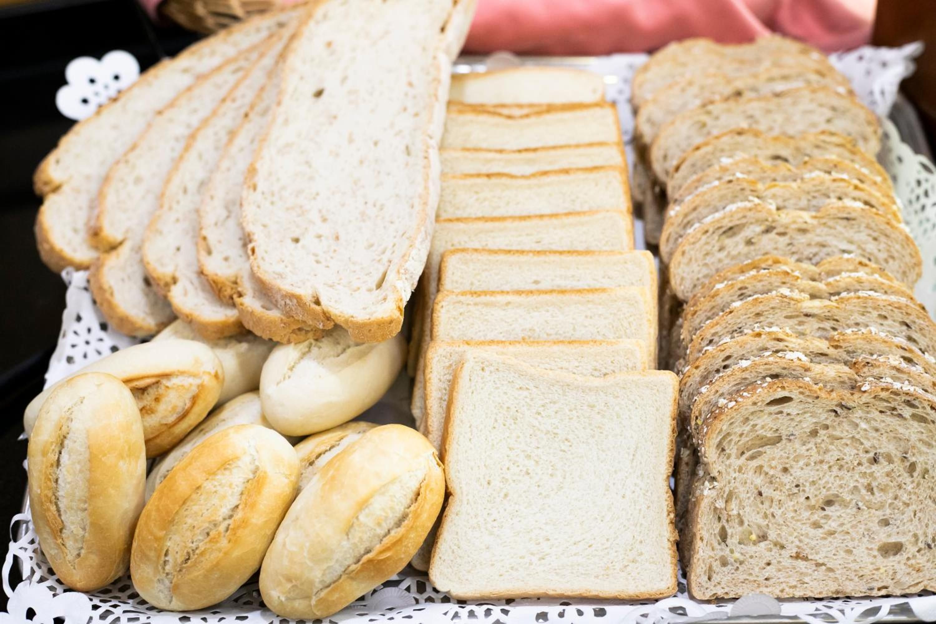 A variety of sliced breads and rolls on a table.