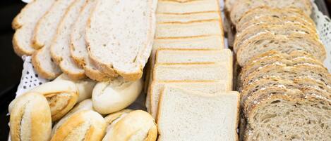 A variety of sliced breads and rolls on a table.