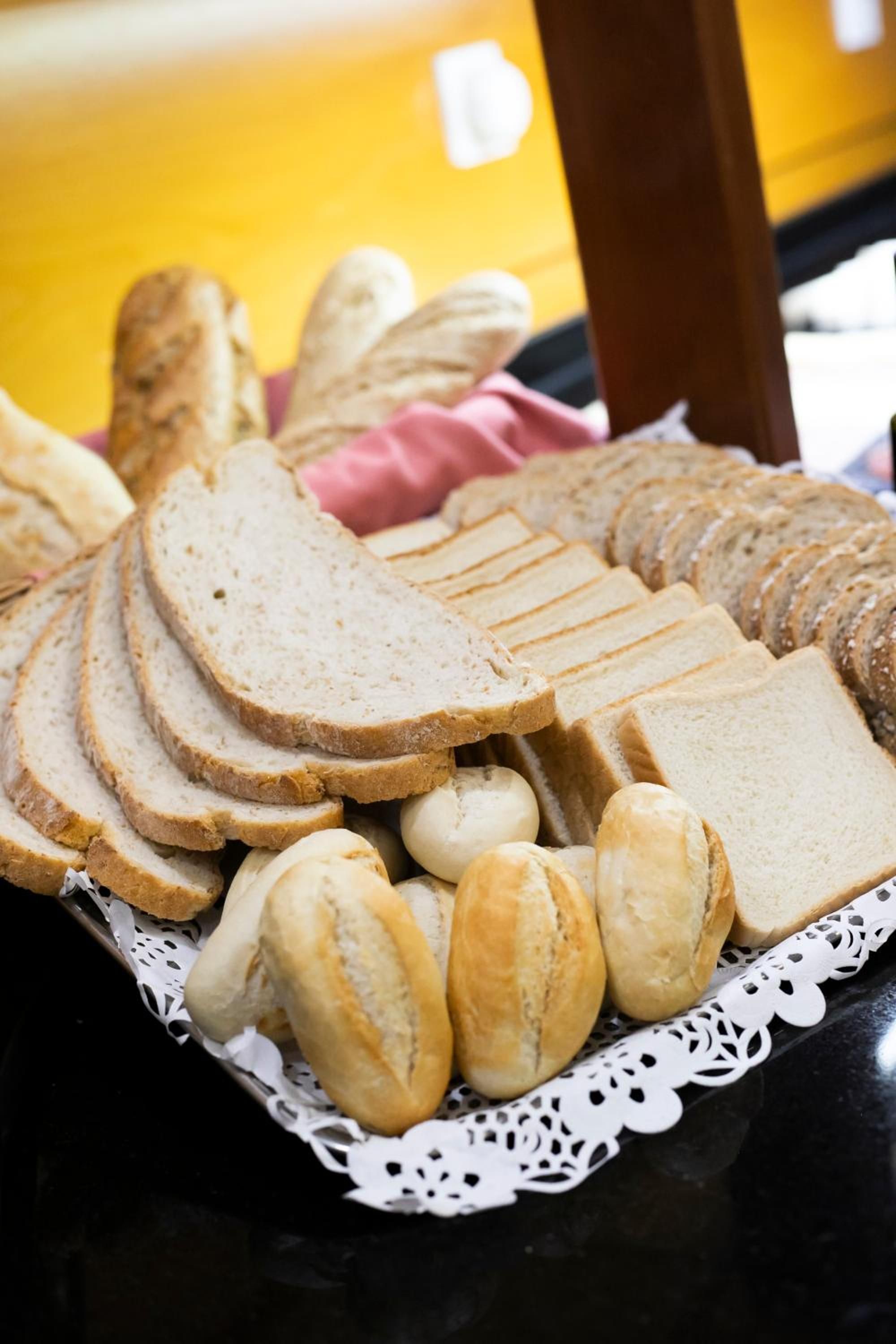A tray of sliced bread and rolls on a table.