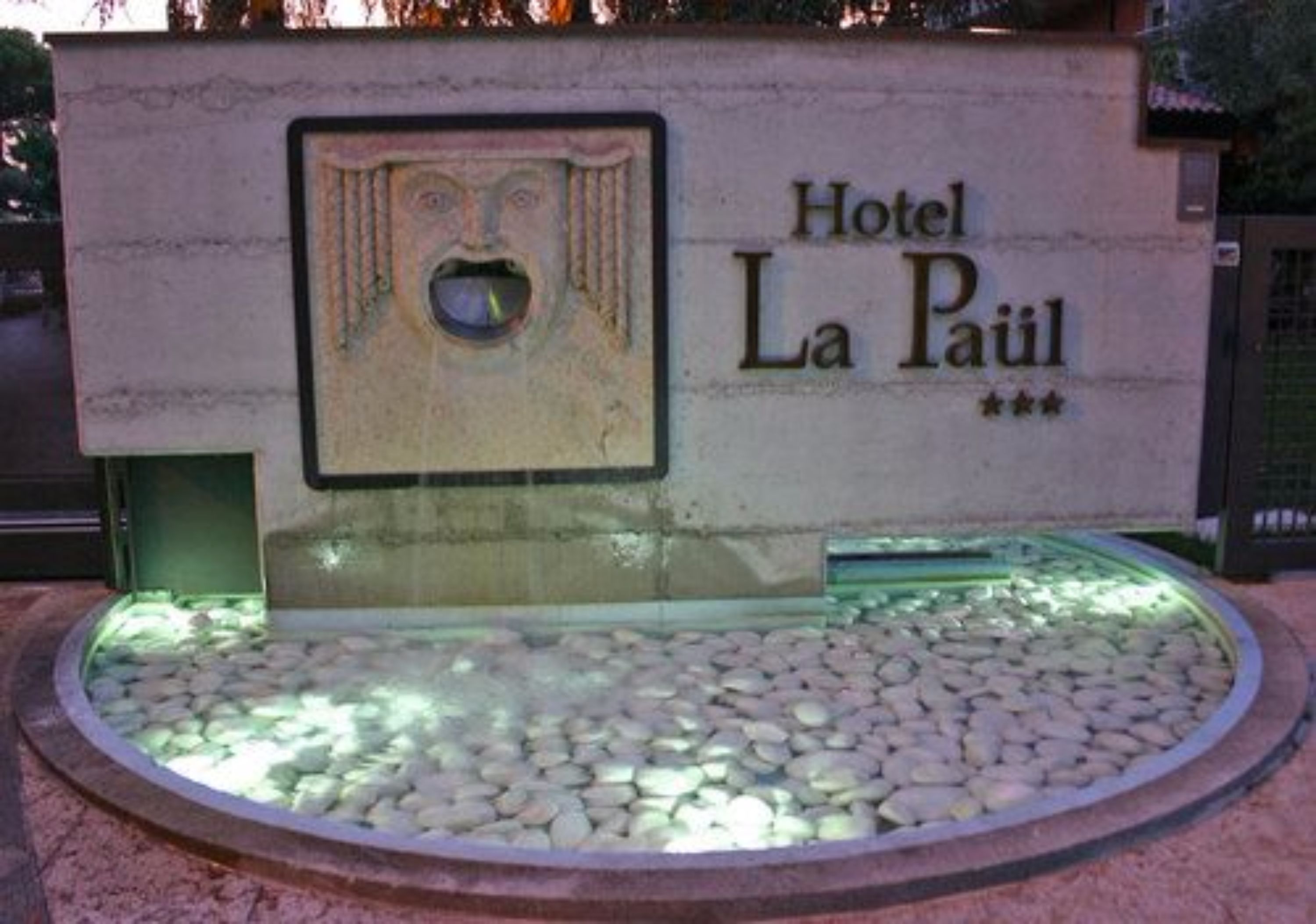 A sign for Hotel La Paul with a circular water feature in front.