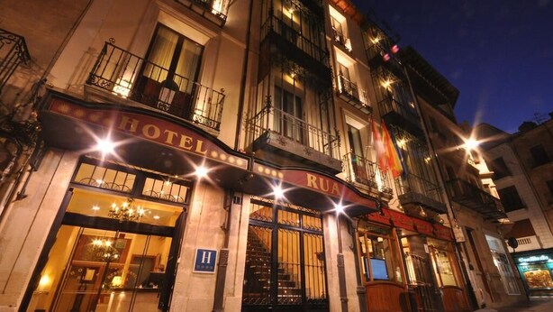 Um hotel com fachada clássica, janelas amplas e uma placa com a inscrição "HOTEL RUA".