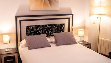A neatly made bed with two pillows, a headboard with a floral pattern, and two bedside lamps.