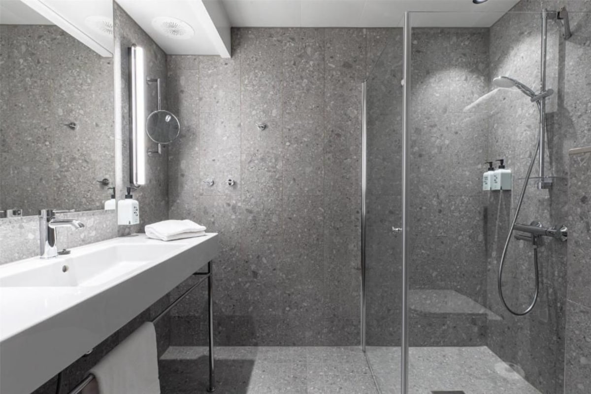 A modern bathroom with a glass shower enclosure, a sink with a mirror, and a towel rack.