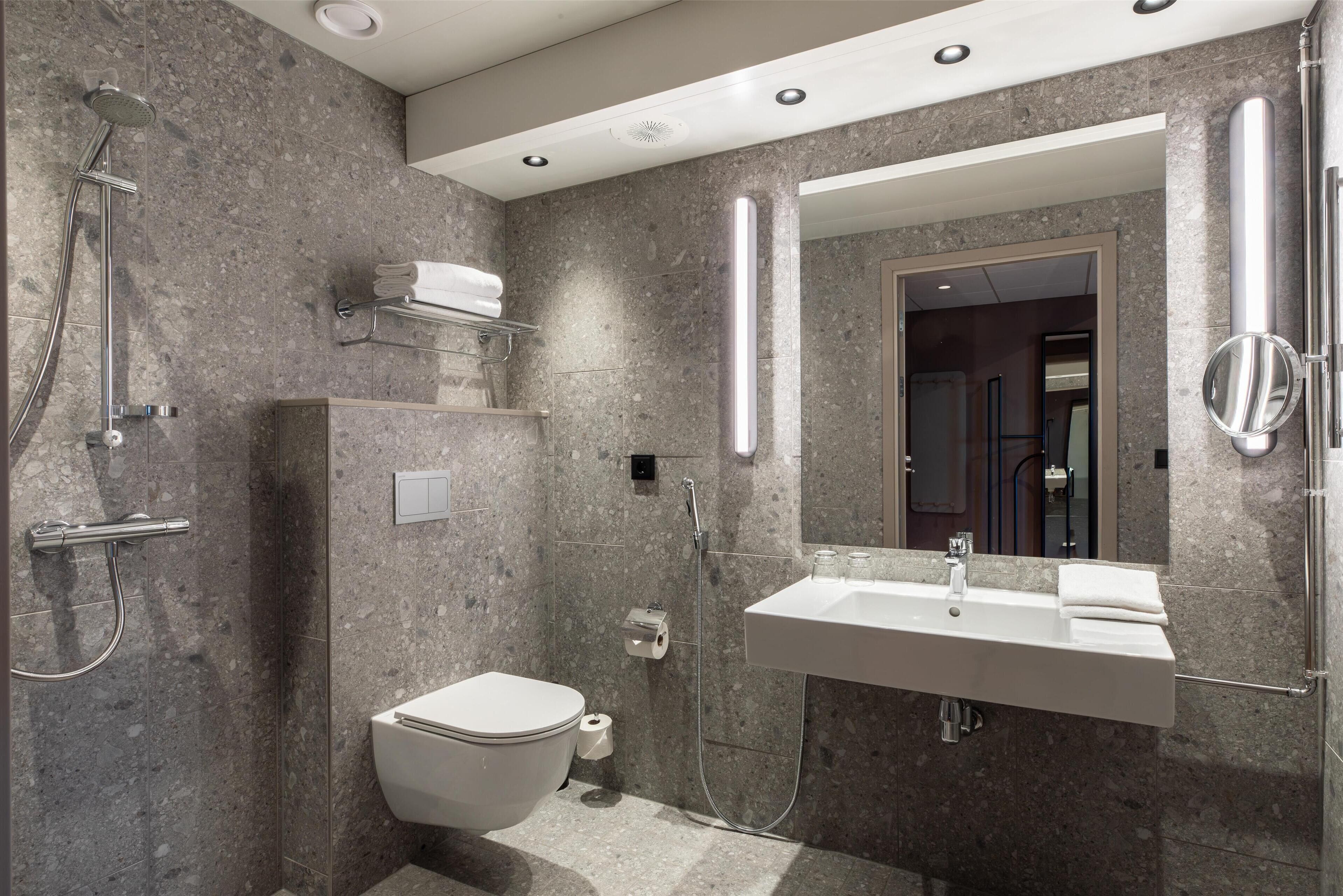 A modern bathroom with a shower, toilet, and sink.