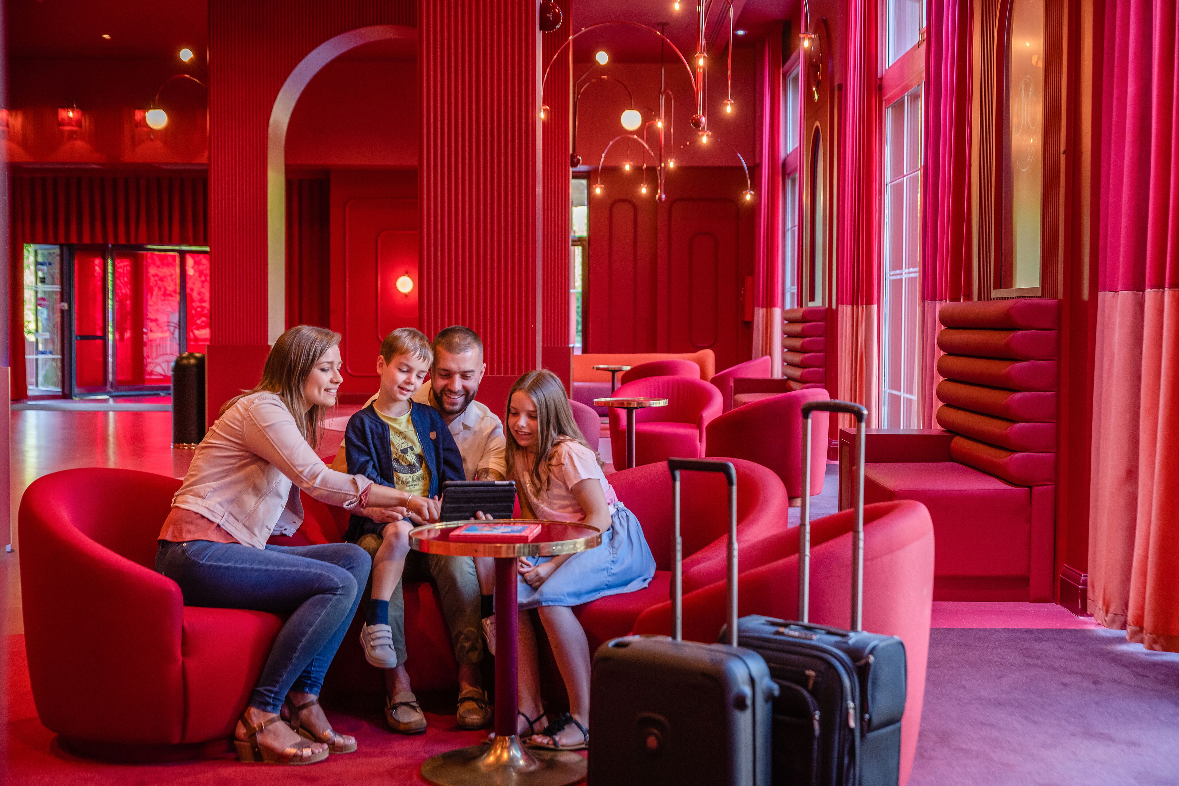 A group of people seated on red couches in a modern interior with a red color scheme and a minimalist design.