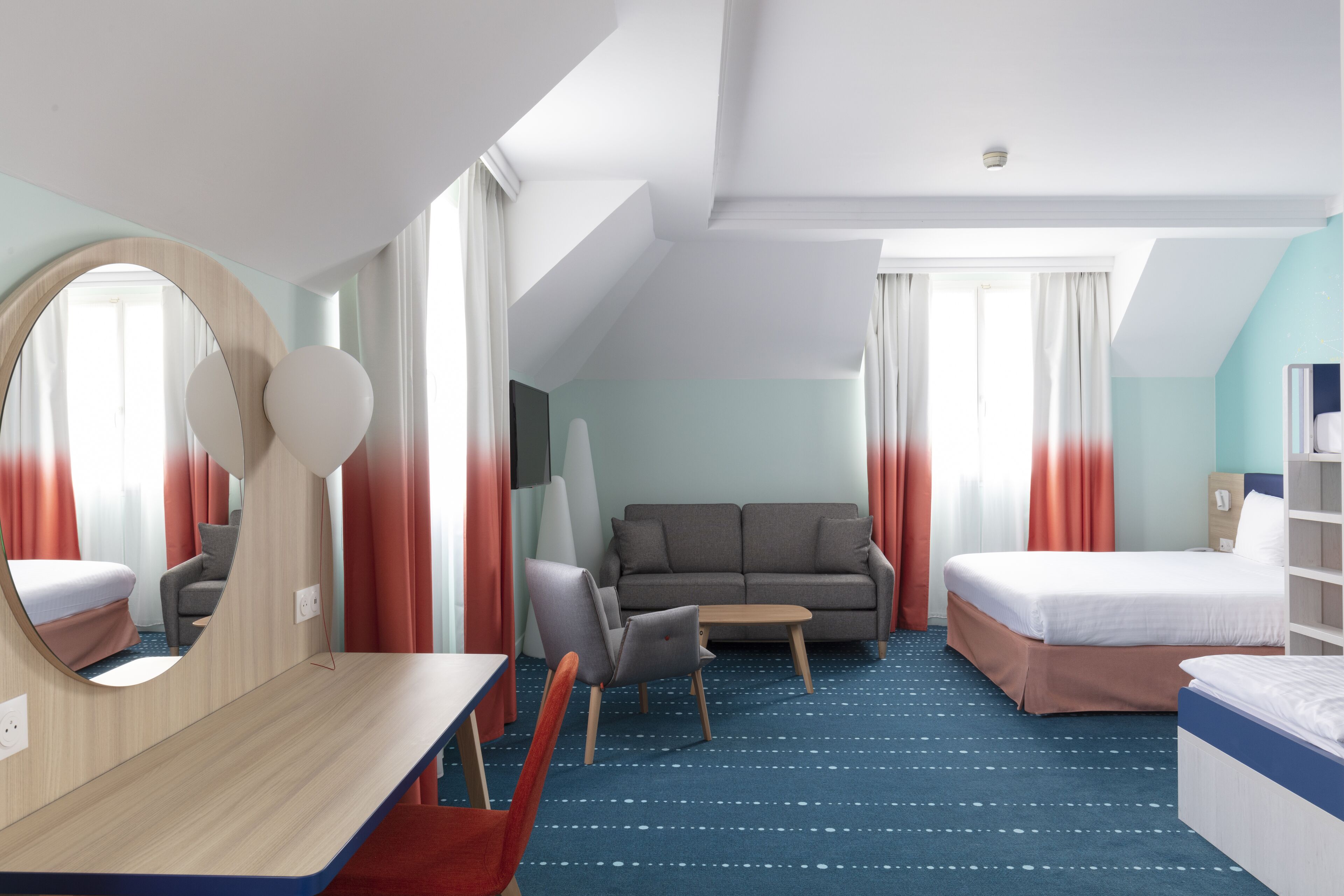 Une chambre d’hôtel moderne équipée d’un lit, d’un canapé, d’un bureau et d’un miroir.