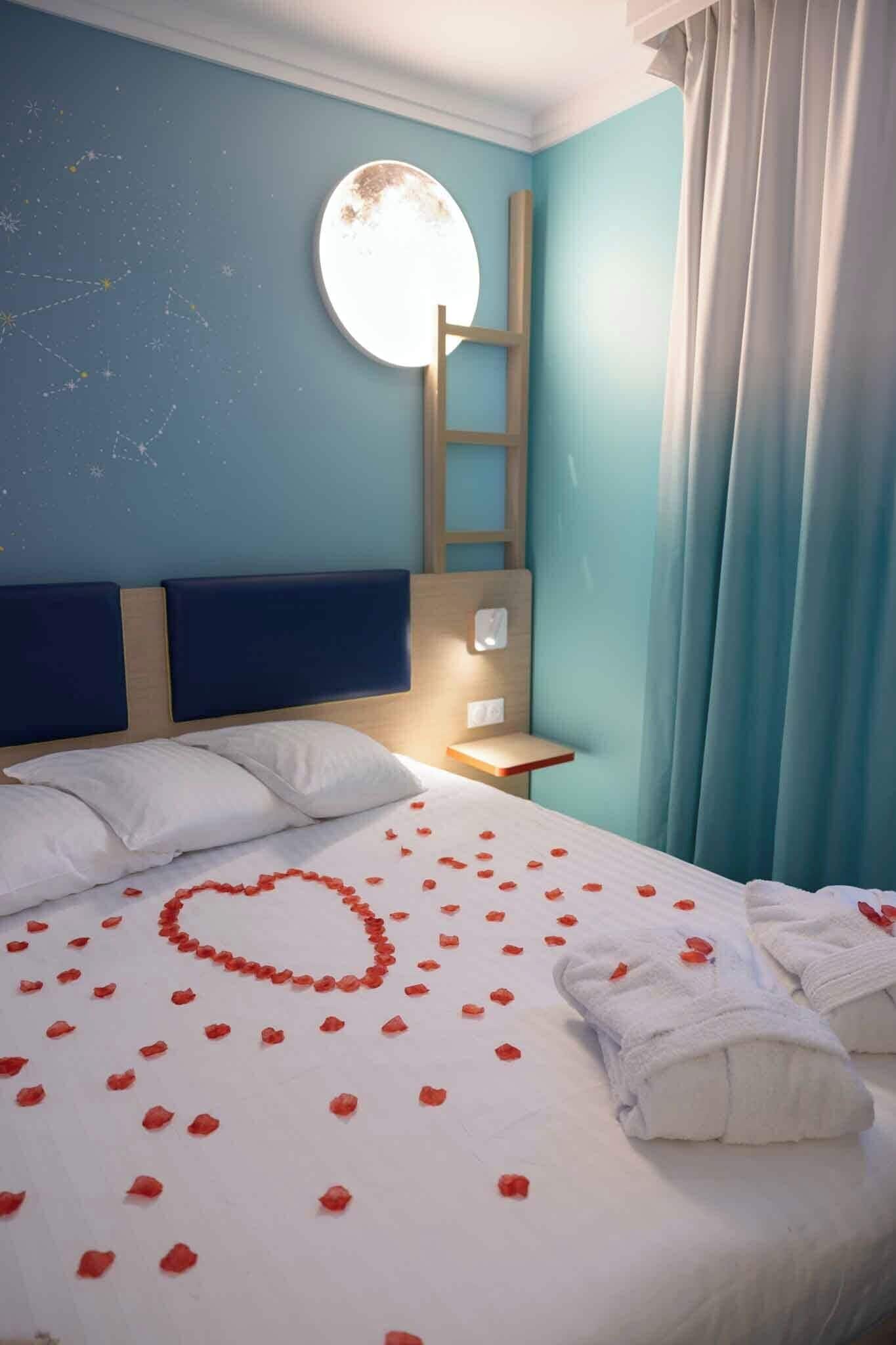 Une chambre d’hôtel avec un lit, un miroir rond, une échelle en bois et une table de chevet.