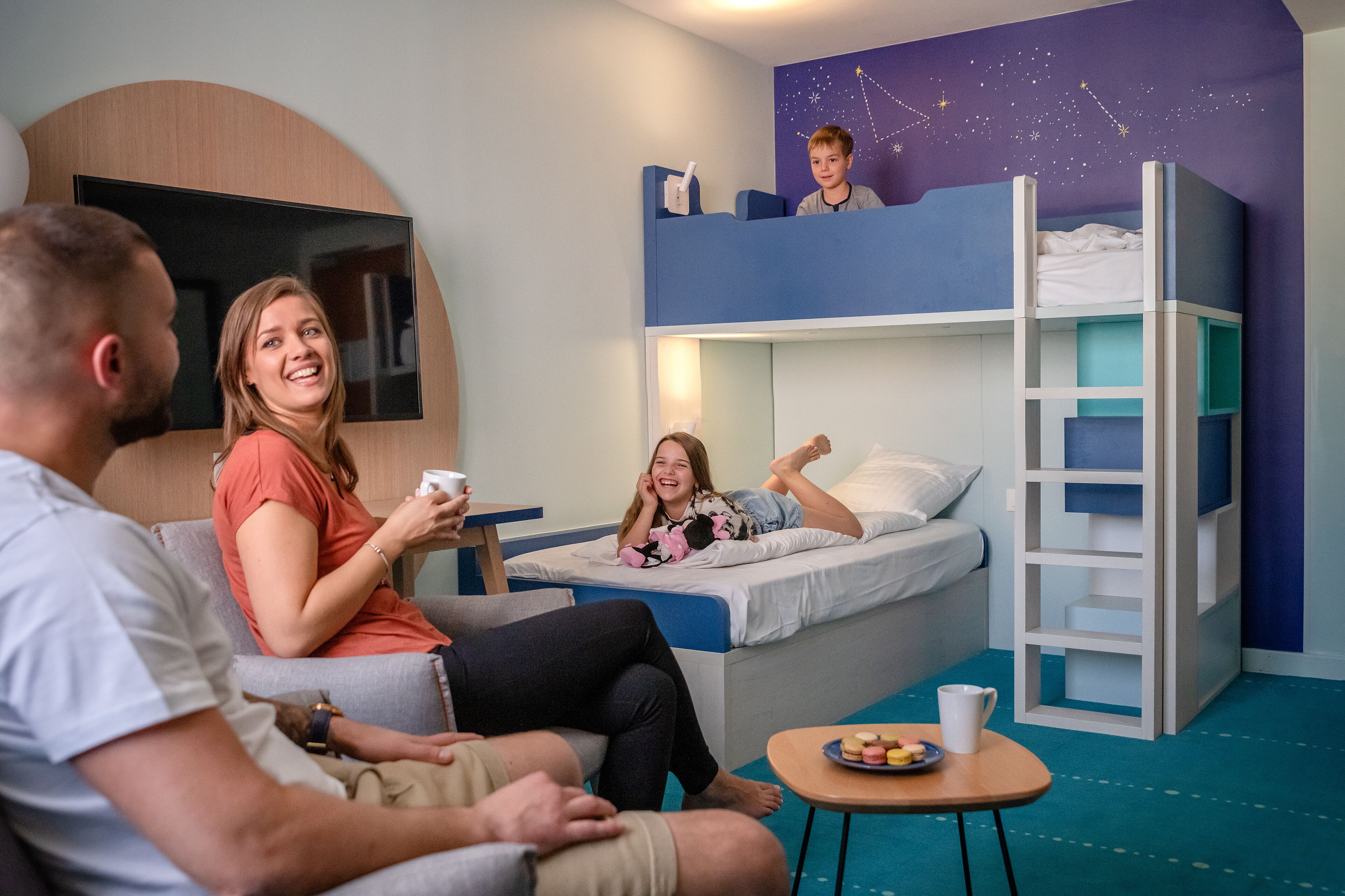 A room with bunk beds, a flat-screen TV, and a starry wall design.