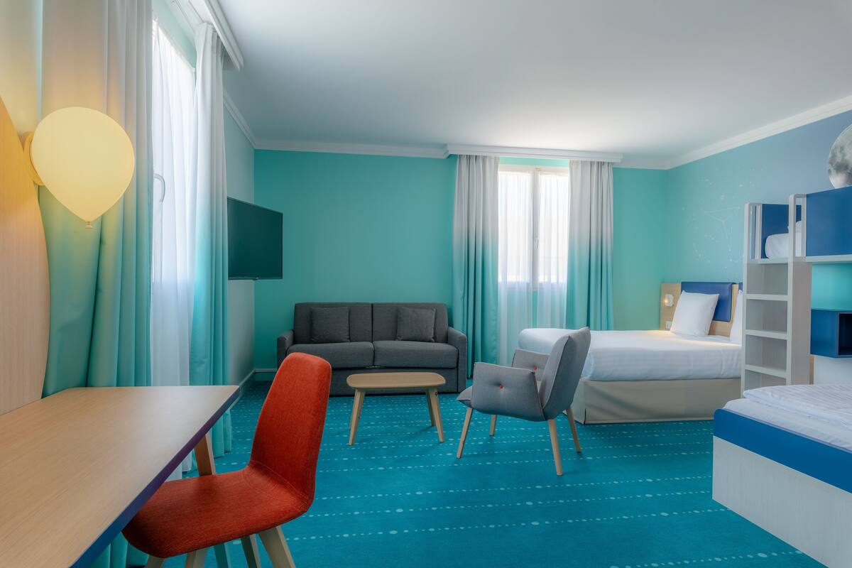 A hotel room with a bed, a sofa, a desk, and a chair.