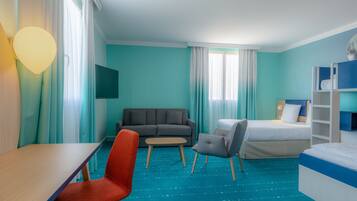 A hotel room with a bed, a sofa, a desk, and a chair.