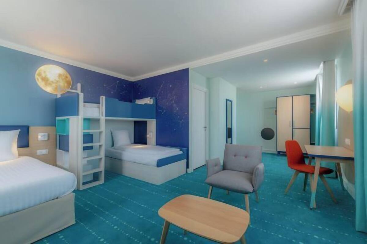 A hotel room with bunk beds, a desk, a chair, and a small table.