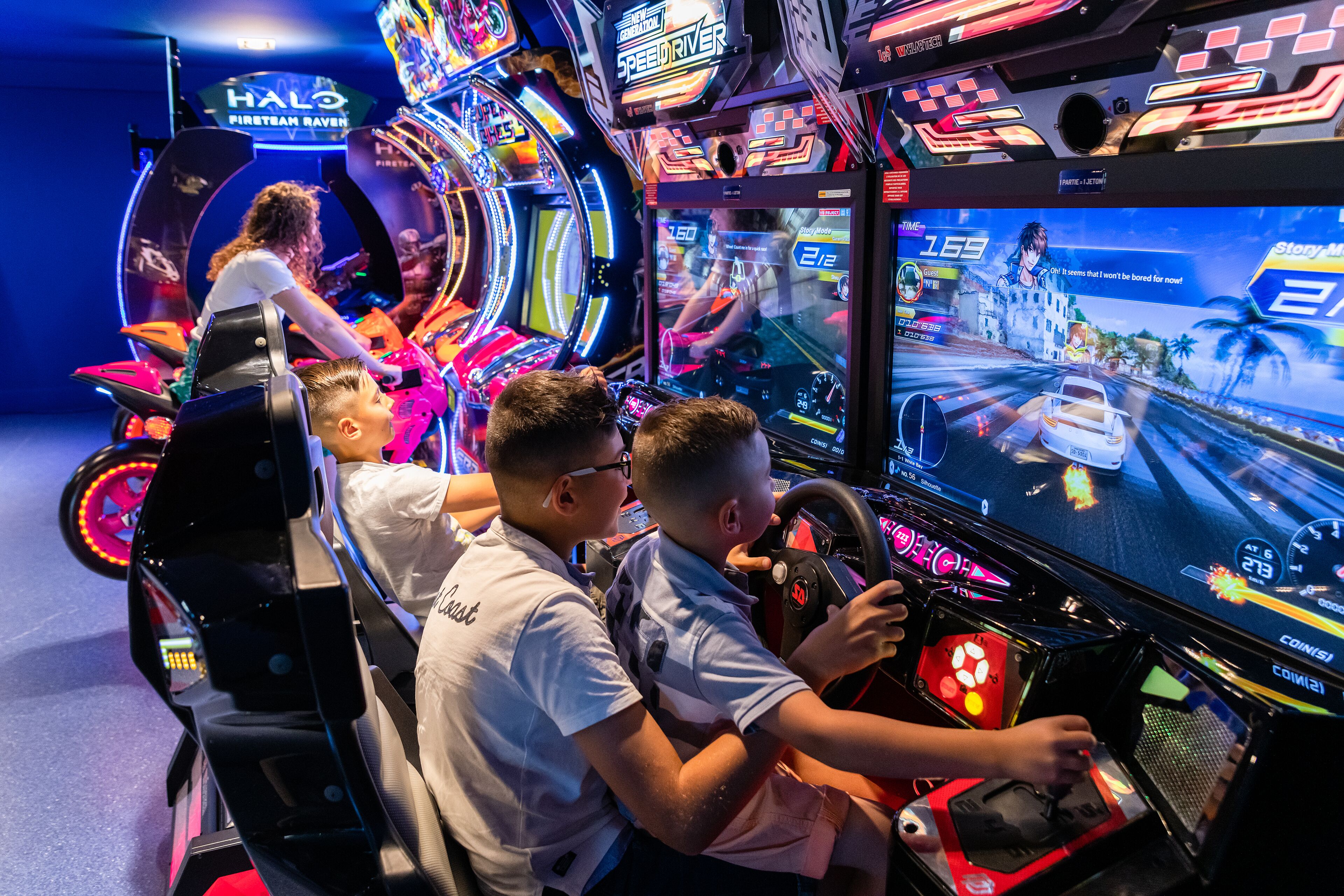 A gaming arcade with multiple racing game machines.