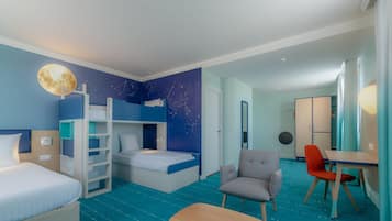 A hotel room with a bunk bed, a desk, a chair, and a small table.