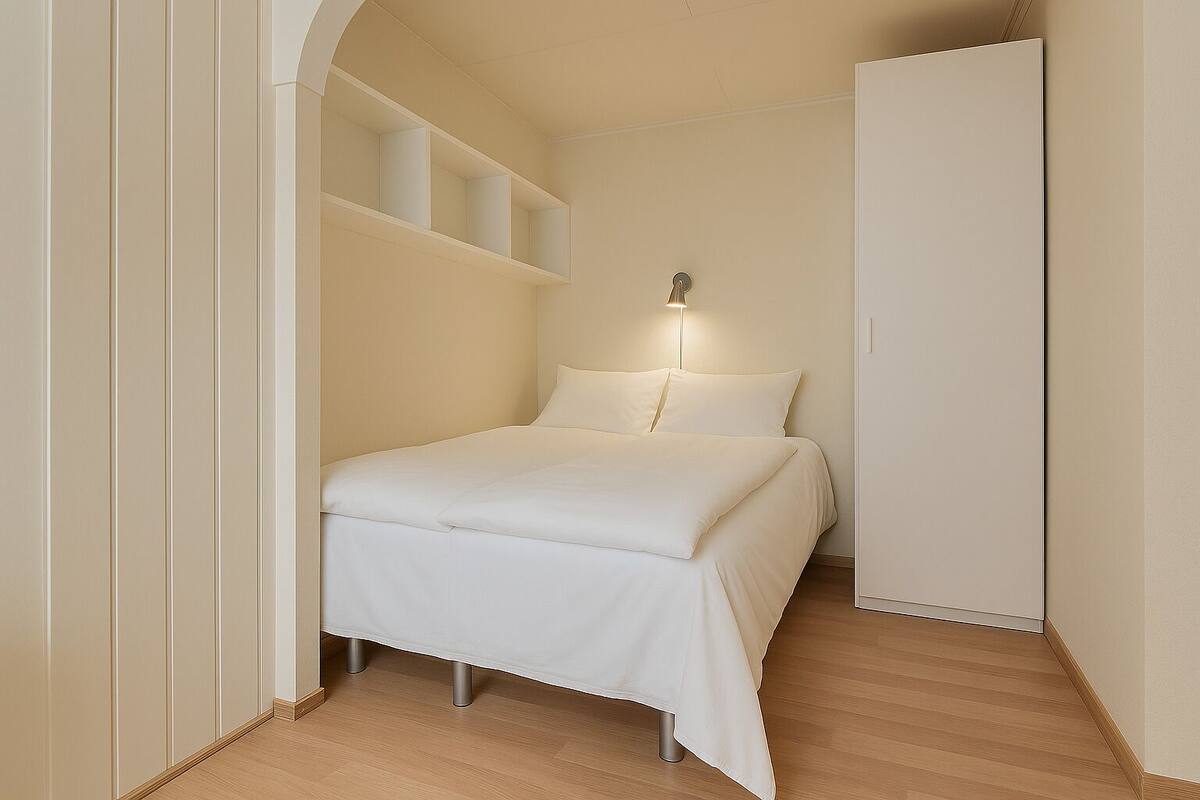 Un dormitorio con cama, mesita de noche y una lámpara fijada a la pared.