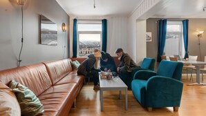 Una sala moderna con un sofá de cuero marrón, sillones turquesa y una mesa de centro blanca.